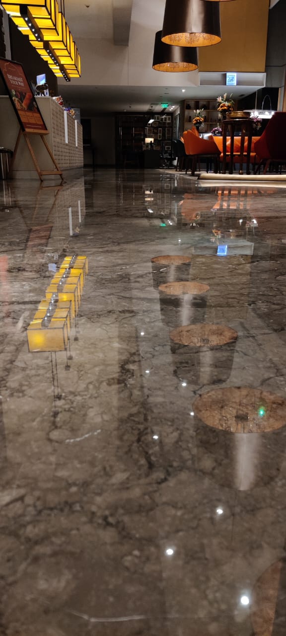 Hotel lounge with pendant lamps and seating reflected in a restored, polished marble floor